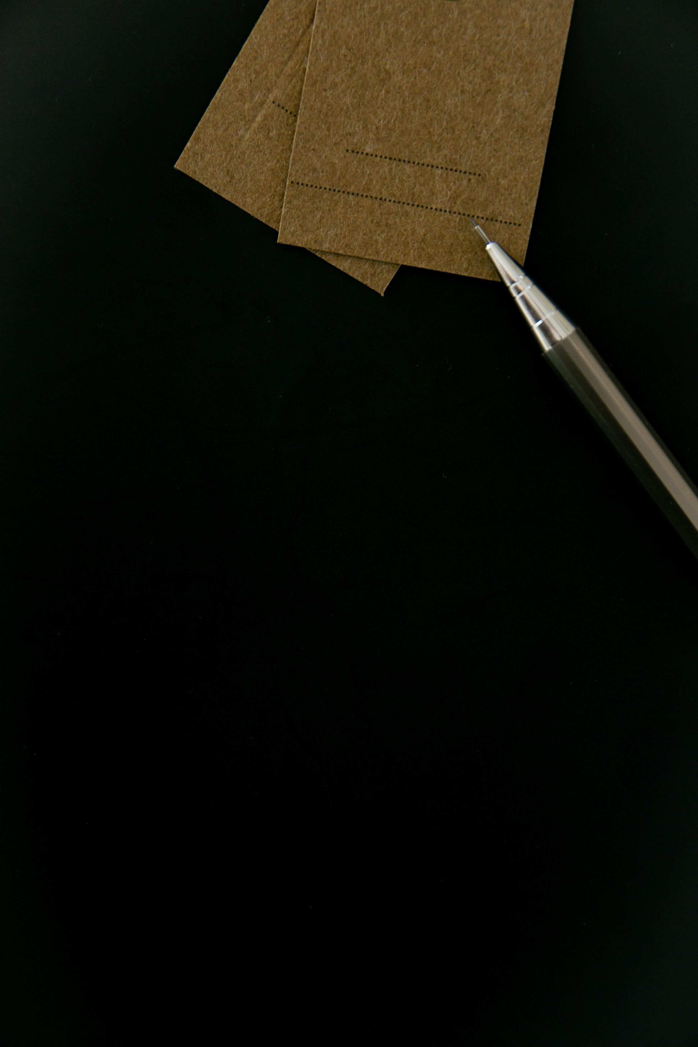 Papierstapel und Stift auf einer dunklen Unterlage